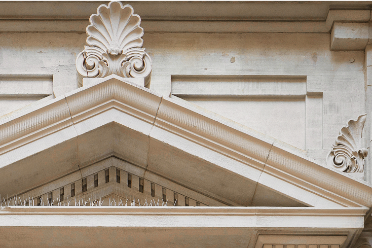 Close-up of a neoclassical building façade with ornate carvings and triangular pediment.