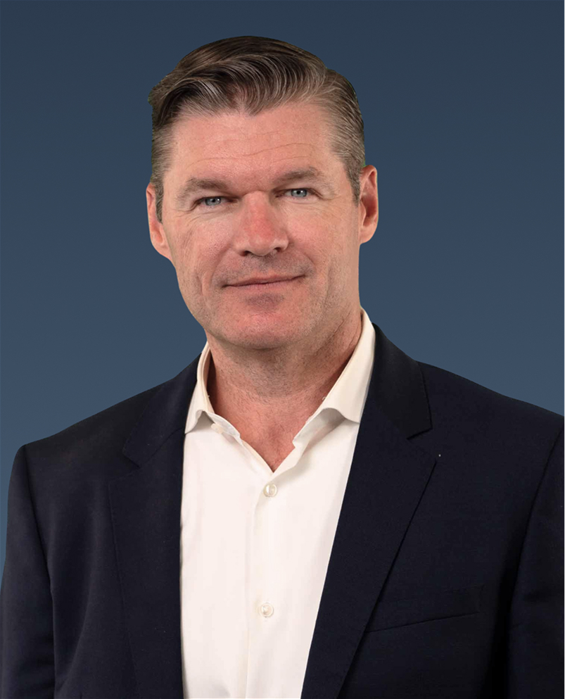 Professional portrait of a man in a dark suit and light shirt, smiling slightly against a blue background.