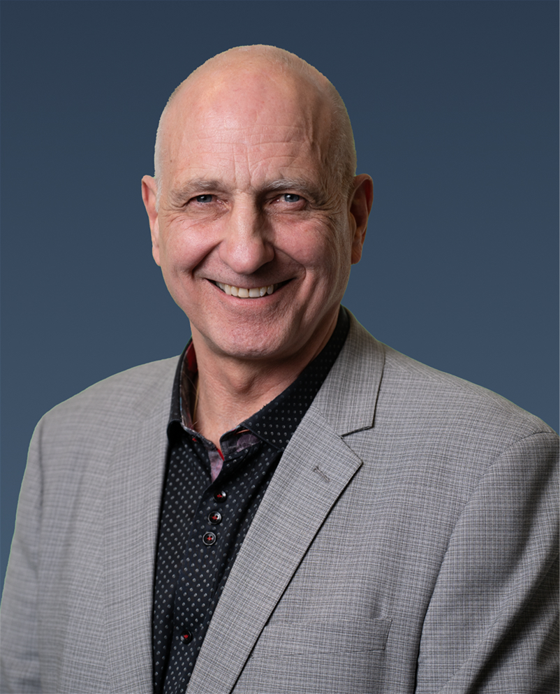 Professional portrait of a man in a gray suit, smiling.