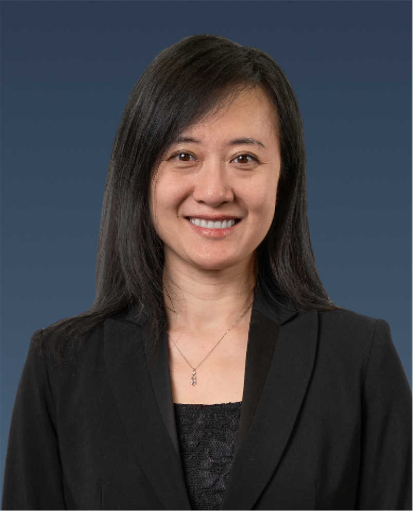 Professional portrait of a woman with dark hair wearing a black blazer, smiling.