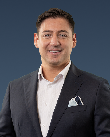 Professional portrait of a man with dark hair, wearing a dark blazer and white shirt with a pocket square.