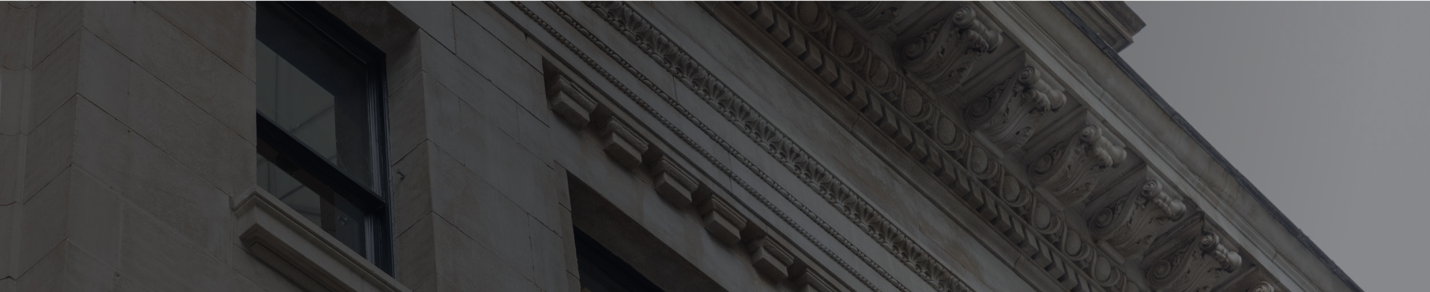 Close-up of a historic building façade with ornate stone carvings and the words ‘OPTIMIZE FINANCIAL GROUP’ engraved above the entrance.